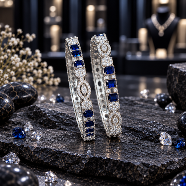 Two silver-tone AD-style bangles with grouped navy blue rectangular accents, clear-looking clusters and pointed oval decorative motifs.