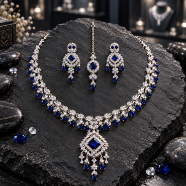 Silver-tone AD-style necklace with a navy blue tilted square pendant, floral-leaf links and blue-drop fringe, alongside chandelier earrings and bindia.