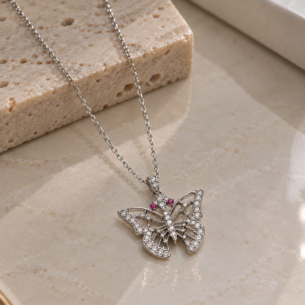 Silver-tone butterfly pendant necklace with openwork wings, clear-accent borders and body, pink antenna-tip details and a fine linked chain.