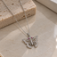 Silver-tone butterfly pendant necklace with openwork wings, clear-accent borders and body, pink antenna-tip details and a fine linked chain.