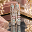 Pair of silver-tone bangles with pastel pink, mint, and clear accents and dangling fringe.