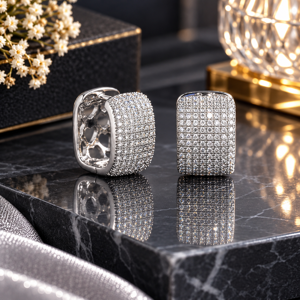 Pair of silver-tone rounded rectangular huggie hoop earrings with clear pavé-style accents and interior heart-shaped cutouts.
