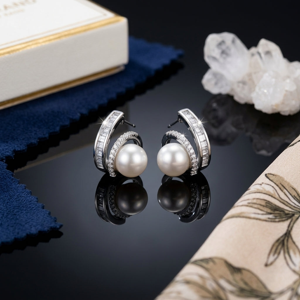 Silver-Tone Pearl Center Baguette & Round Pavé CZ Swirl Crescent Stud Earrings pair on dark reflective surface with white quartz crystal cluster and navy blue velvet jewelry pouch backdrop