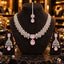 Silver-tone floral necklace with a square pink centre and pink teardrop pendant, matching pink chandelier earrings and floral maang tikka with a pink drop, displayed on dark stands.