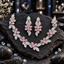 Silver-tone floral vine necklace with pink oval petals, clear-looking flower centres and decorative leaves, with matching elongated earrings.