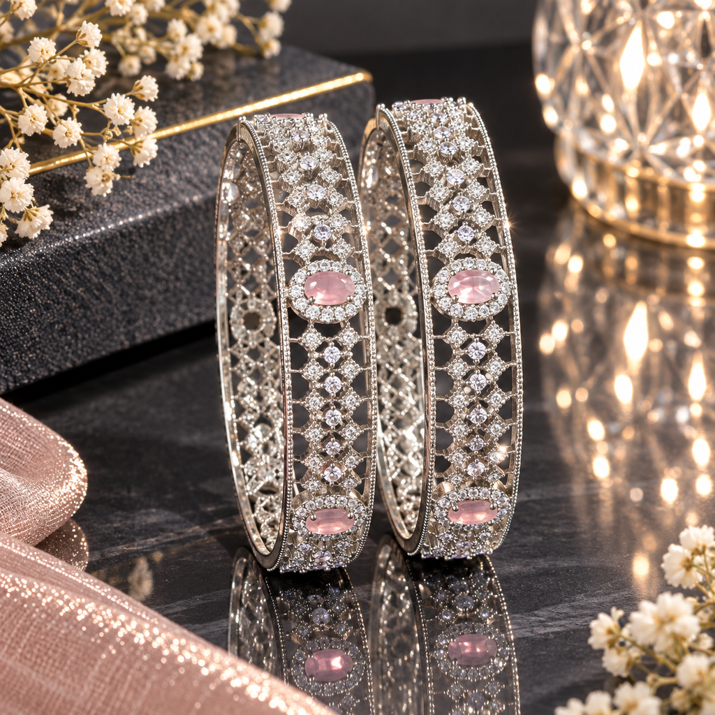 Pair of silver-tone openwork bangles with pink oval accents and clear faceted details.
