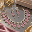 Silver-tone necklace and matching drop earrings with pink oval accents, clear floral clusters, leaf-shaped details, and decorative curls.