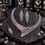 Silver-tone necklace, long tiered earrings and chain bindia with pink rectangular accents and cascading clear teardrop details.