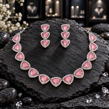 Silver-tone AD-style necklace with linked pink rounded triangular centres and clear-looking halo borders, alongside matching three-tier earrings.