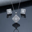 Silver-Tone Princess-Cut Baguette CZ Multi-Layer Diamond Pendant Necklace and Earrings Set flat lay on dark grey mirror surface with grey backdrop showing large rhombus diamond pendant with 4-stone princess-cut CZ quad cluster center inner baguette CZ channel ring and outer round micro-pave CZ halo on silver box chain flanked by matching square stud earrings with mirror reflections below