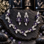 Silver-tone floral vine necklace with purple oval petals, clear-looking flower centres and decorative leaves, with matching elongated earrings.