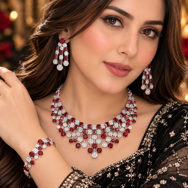 Model wearing a silver-tone red accent necklace, tiered earrings and matching bracelet with rectangular red details and clear-accent clusters.