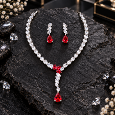 Silver-tone marquise-leaf necklace with three red centre accents, a descending clear-leaf detail and red teardrop drop, with matching earrings.
