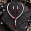 Silver-tone marquise-leaf necklace with three red centre accents, a descending clear-leaf detail and red teardrop drop, with matching earrings.