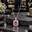 Silver-tone linked-chain necklace with a pink-red ruby-coloured rectangular centre, rounded segmented clear-accent halo and accented bail.