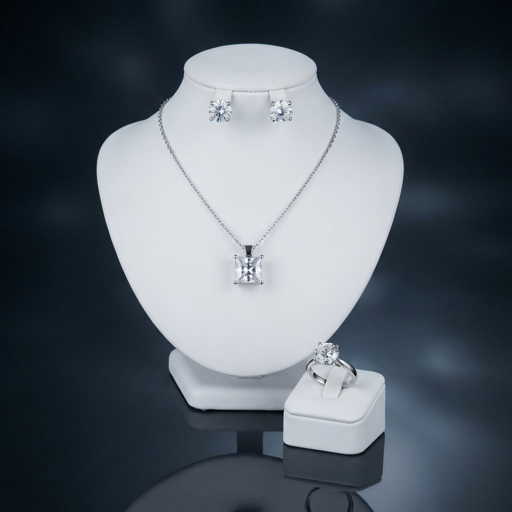 Silver-tone set displayed with a square-cut pendant necklace, round stud earrings, and a matching ring.