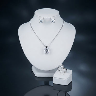 Silver-tone set displayed with a square-cut pendant necklace, round stud earrings, and a matching ring.