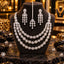Silver-tone three-layer necklace with floral clusters and oval clear accents, matching chandelier earrings and a maang tikka with floral strands and teardrop drops, displayed on a dark bust.