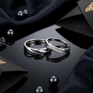 Silver-Tone Twisted Wave Ridge Band & Pavé CZ Stripe Couple Rings Set His & Hers on black reflective surface with dark geometric paper origami and black pearl beads backdrop