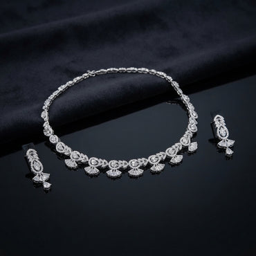 Silver White CZ Baguette Fan Leaf Necklace and Pear Drop Earrings Bridal Set — rhodium silver-tone 2-piece bridal set with continuous alternating baguette fan-leaf motif necklace with pear CZ centers flanking marquise CZ and radiating baguette fan drops and matching open marquise leaf stud with large pear CZ drop earrings displayed on dark black satin surface with mirror reflection