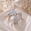 Silver-Tone White CZ Cushion Halo & Pavé Fern Leaf Bypass Open Ring on champagne satin fabric with crystal light orb and dried white baby's breath flowers backdrop