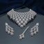 Silver White CZ Halo Pear Graduated Wide Bib Choker Necklace Earrings & Maang Tikka Grand Bridal Set on black mirror surface with dark navy blue silk drape backdrop