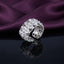 Silver White CZ Marquise Floral Cluster Open Cuff Wide Band Statement Ring side profile on dark grey mirror surface with deep purple amethyst velvet backdrop showing full open cuff profile and intricate 6-petal flower cut-out filigree inner structure with 3D marquise-petal flower cluster outer face in rhodium silver with mirror reflection below