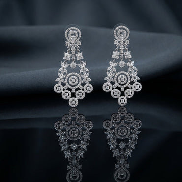 Silver White CZ Marquise Floral Wreath and Circle Medallion Grand Chandelier Drop Earrings — rhodium silver-tone grand bridal chandelier earrings with pear CZ halo disc stud marquise CZ bow connector open marquise CZ floral spray full marquise CZ leaf wreath and elaborate 5-medallion base with cushion white CZ centers in full CZ micro-pavé displayed on dark charcoal satin backdrop with mirror surface reflection
