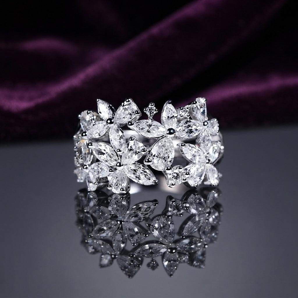 Silver White CZ Marquise Multi-Flower Cluster Wide Band Statement Ring angled top view on dark grey mirror surface with deep purple amethyst velvet backdrop showing three large 3D sculptural marquise-petal flowers with pear and round white CZ accents across full band in rhodium silver with full mirror reflection below