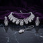 Silver White CZ Peacock Feather Filigree Choker Earrings and Maang Tikka Bridal Set flat lay on dark black marble with purple velvet backdrop showing 7 graduated peacock feather filigree teardrop motifs with scrolling vine white CZ and oval solitaire centres matching drop earrings and maang tikka