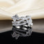 Silver White CZ Triple Pave Band Dual Butterfly Wide Statement Ring top view standing on dark black mirror surface with cream ivory satin fabric backdrop showing three parallel open micro-pave white CZ rails with small left butterfly spanning top and middle rail and larger right butterfly spanning middle and lower rail in rhodium silver with sharp mirror reflection below