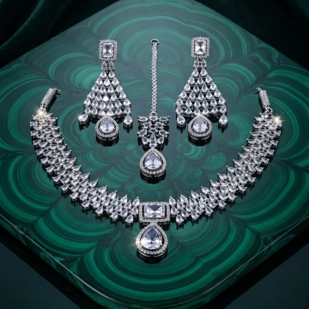 Silver White CZ Tiered Waterfall Pear Choker Necklace Earrings & Maang Tikka Bridal Set on green malachite tray with dark green velvet backdrop