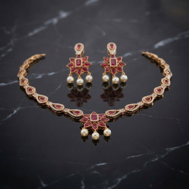 South Indian-style red-and-green floral pendant necklace with white pearl-look beads and matching drop earrings.