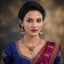 Model wearing a South Indian-style gold-tone floral necklace with white pearl-look beads and matching red-and-green drop earrings.