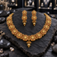 Gold-tone South Indian-style necklace with round floral medallions, champagne-coloured oval accents and a ribbed oval centre drop, with matching stacked-disc earrings.