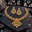 South Indian-style gold-tone necklace with deep-pink and green oval accents, an ornate scrollwork pendant and cream-white pearl-look drops, with matching earrings.
