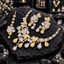 Gold and silver-tone clear-accent necklace with heart and floral-inspired panels and cascading teardrops, matching double-drop earrings and bindia.