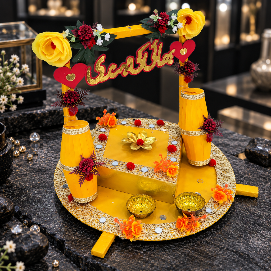 Round yellow mehndi ceremony tray with floral Urdu-lettered frame, two yellow drum-style decorations, raised square centre, gold-tone trim and two small bowls.